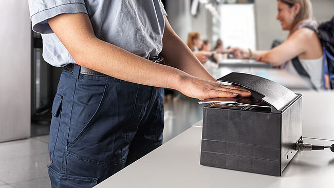 Image of Border Control Officer using a machine to scan and authenticate a KINEGRAM-secured passport