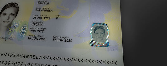 Illustration of the KINEGRAM PHOTOGRAPH technology for highly secure secondary images in identity documents. It shows a KINEGRAM PHOTOGRAPH secondary portrait on a sample passport page. The secondary and primary portraits are clearly identical.