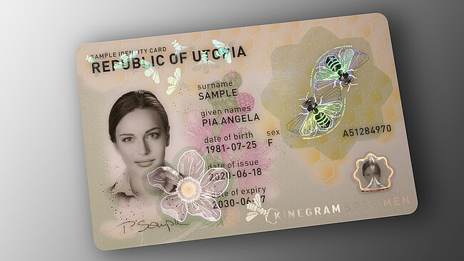 Image of polycarbonate ID card with embedded KINEGRAM security feature showing a bee design